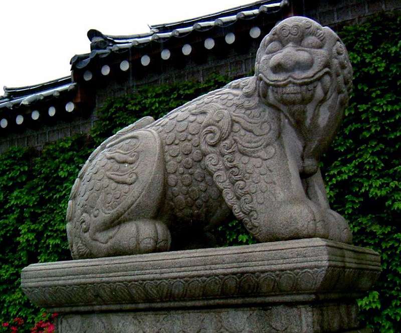 statue of a lion dog outside a green wall